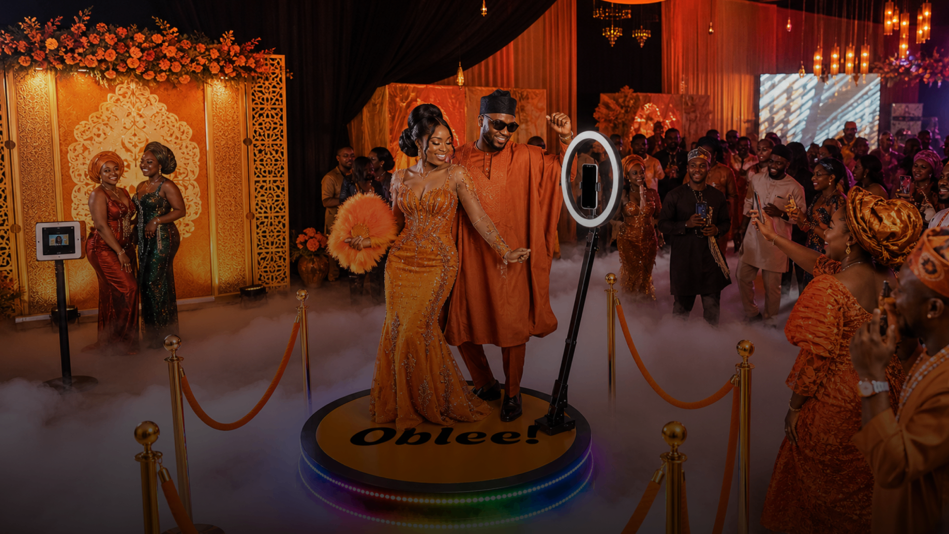 Couple celebrating on an Oblee 360 photobooth platform with Ankara backdrop